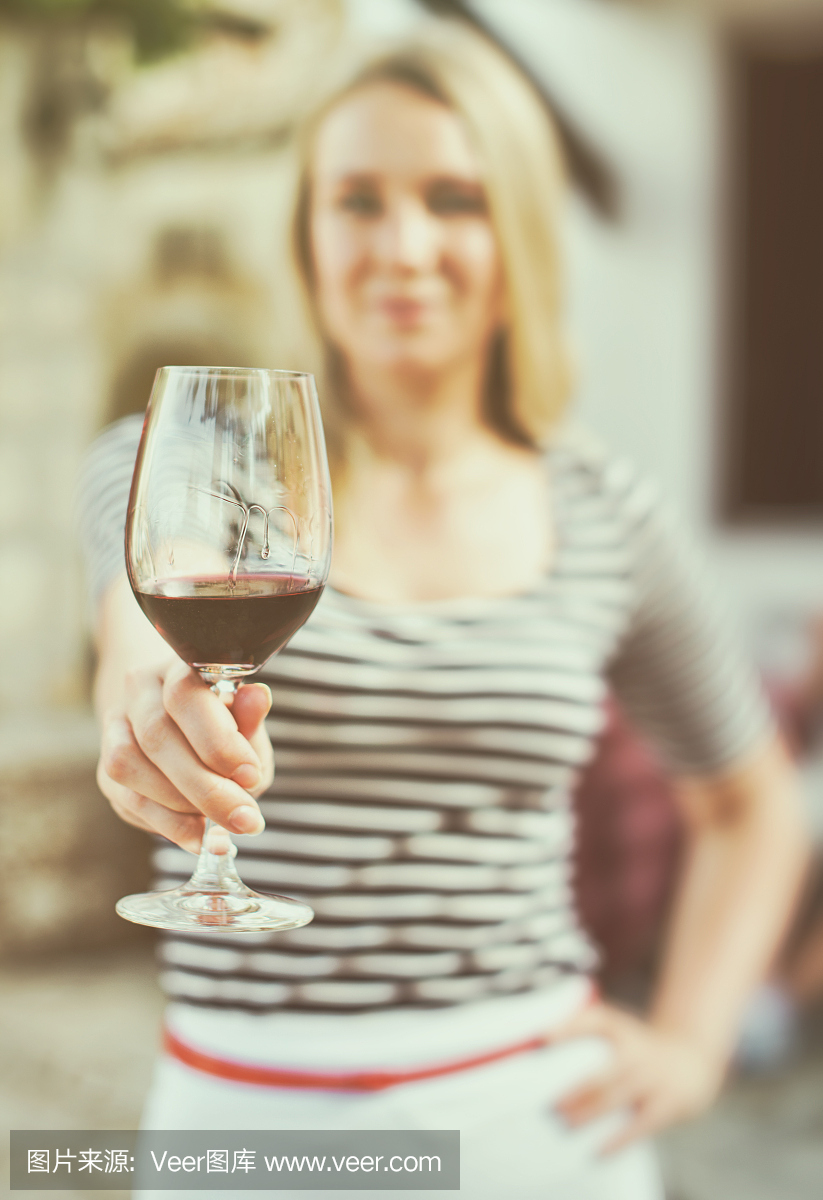 一個女人在室外遞上一杯紅酒。復古的效果。